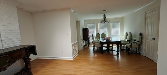 dining space with visible vents, light wood-style flooring, an inviting chandelier, ornamental molding, and baseboards