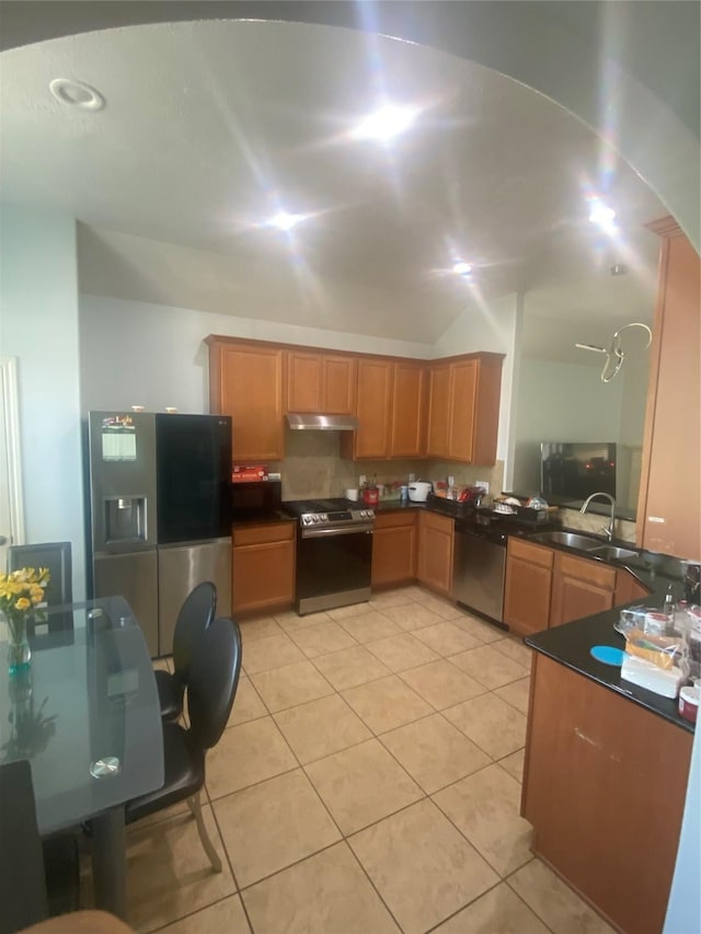 kitchen with light tile patterned floors, dark countertops, appliances with stainless steel finishes, under cabinet range hood, and a sink