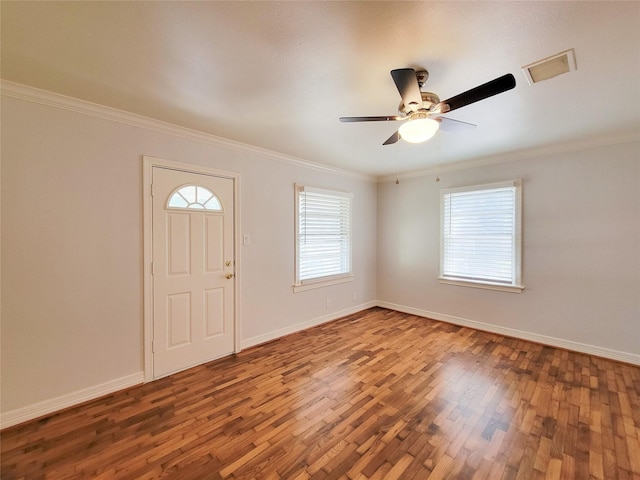 entrance foyer featuring visible vents, ornamental molding, wood finished floors, baseboards, and ceiling fan