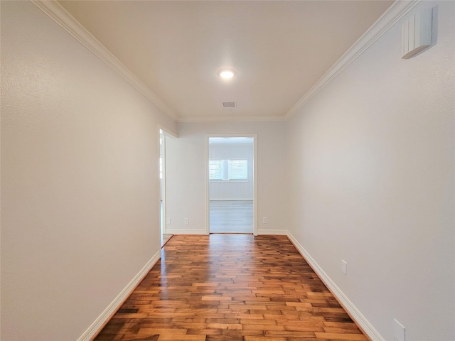 empty room with crown molding, baseboards, and wood finished floors