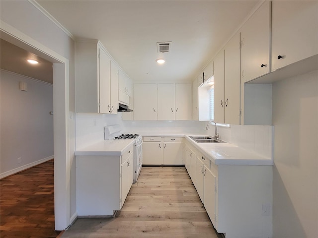 kitchen featuring visible vents, white gas stove, a sink, light wood finished floors, and decorative backsplash