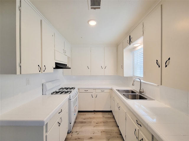 kitchen with visible vents, white gas stove, under cabinet range hood, light wood-style flooring, and a sink