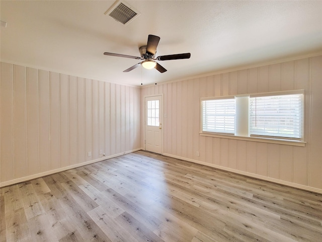 empty room featuring visible vents, baseboards, wood finished floors, and a ceiling fan