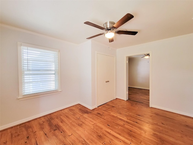 spare room with a ceiling fan, baseboards, light wood finished floors, and ornamental molding