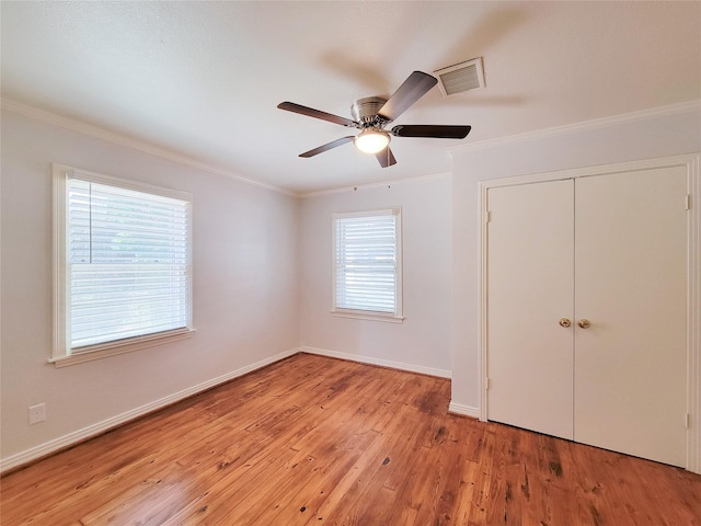 unfurnished bedroom featuring crown molding, light wood-style flooring, baseboards, and visible vents