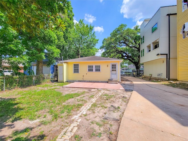 back of property with entry steps, concrete driveway, and fence