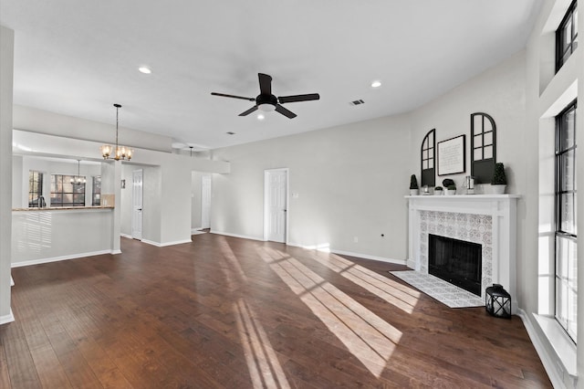 unfurnished living room with recessed lighting, dark wood-type flooring, a tile fireplace, baseboards, and ceiling fan with notable chandelier