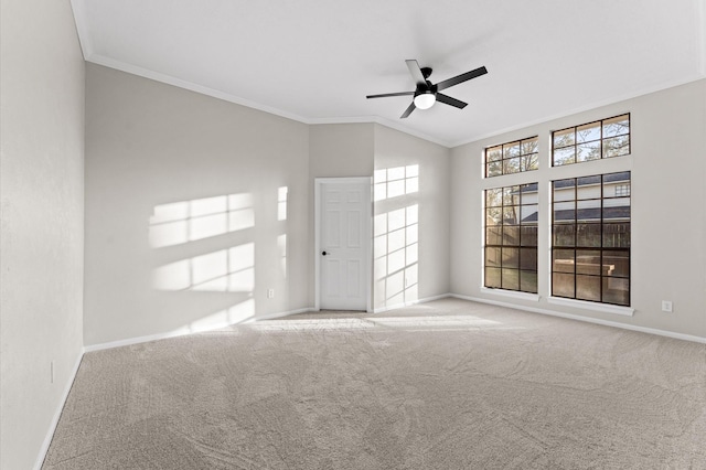 carpeted spare room with ceiling fan, baseboards, vaulted ceiling, and crown molding