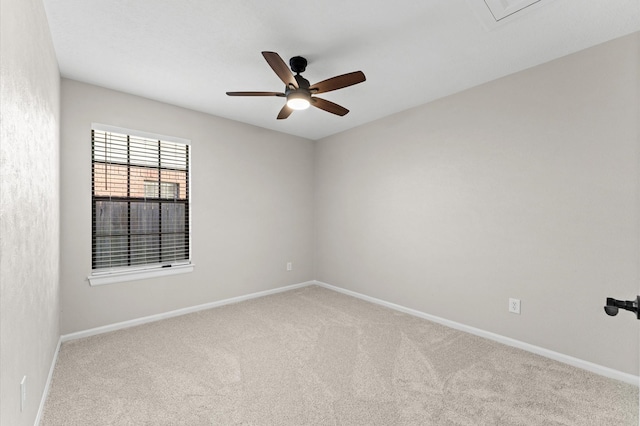 carpeted spare room with a ceiling fan and baseboards