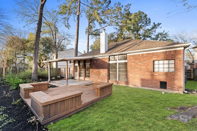 back of property featuring brick siding, a chimney, a lawn, a fenced backyard, and a wooden deck