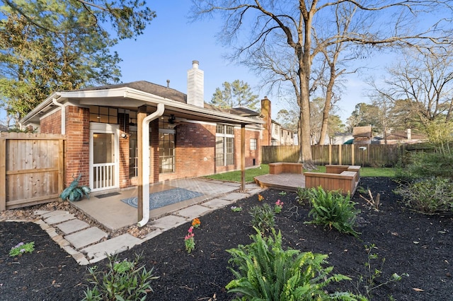 back of property with a patio, a fenced backyard, brick siding, a ceiling fan, and a chimney