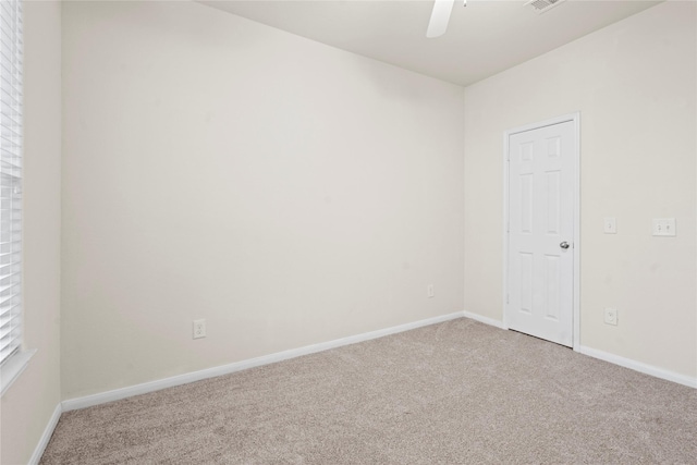 carpeted spare room with visible vents, a ceiling fan, and baseboards