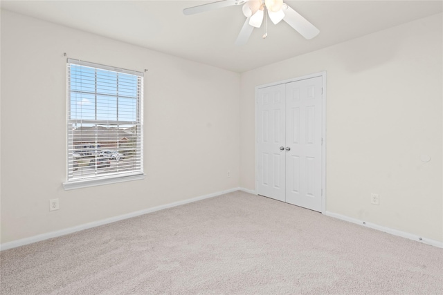 unfurnished bedroom with a ceiling fan, baseboards, a closet, and light colored carpet