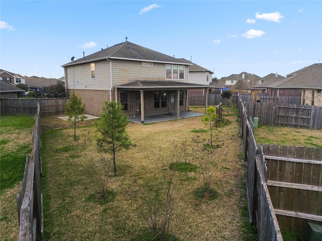 back of house featuring brick siding, a fenced backyard, a lawn, and a patio