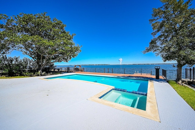 view of swimming pool featuring a patio, a water view, fence, and a pool with connected hot tub