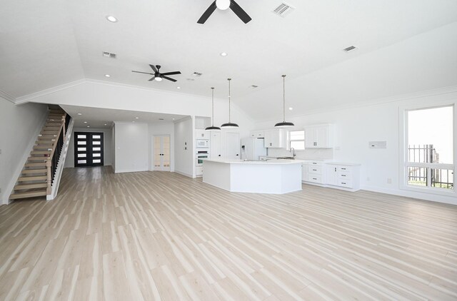 unfurnished living room featuring ornamental molding, visible vents, vaulted ceiling, and light wood-style flooring