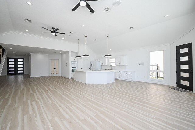 unfurnished living room featuring vaulted ceiling, a sink, and light wood-style flooring