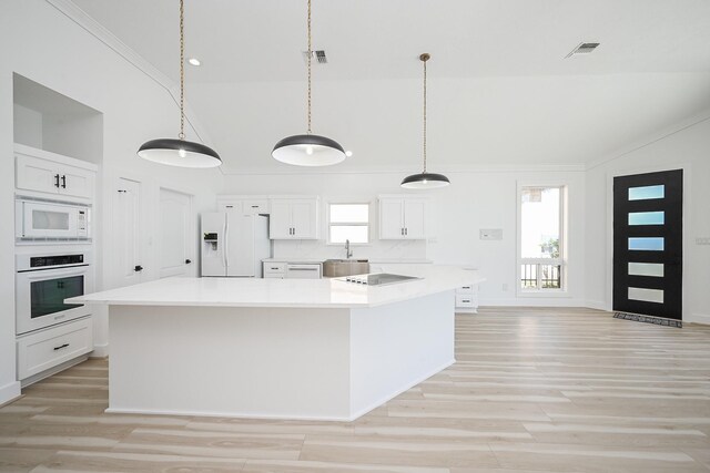 kitchen featuring lofted ceiling, white appliances, plenty of natural light, and light countertops