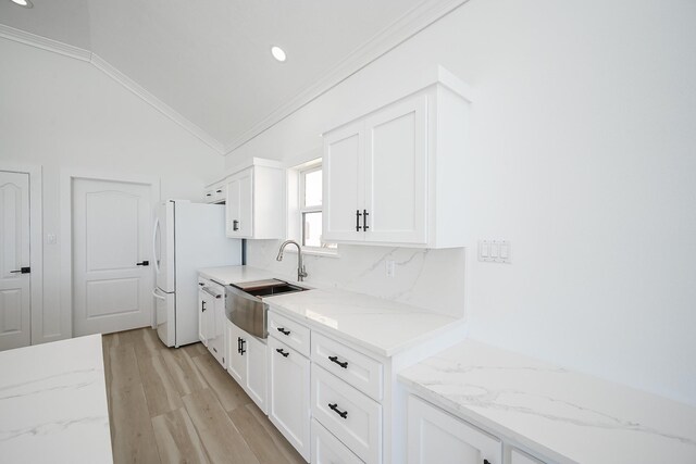 kitchen featuring ornamental molding, vaulted ceiling, a sink, and tasteful backsplash