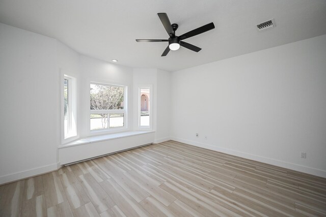 spare room featuring light wood-type flooring, baseboards, visible vents, and ceiling fan