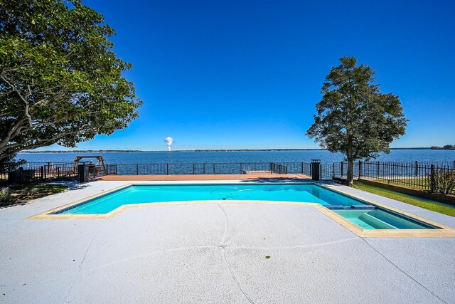 view of pool with a patio area, a fenced backyard, a pool with connected hot tub, and a water view