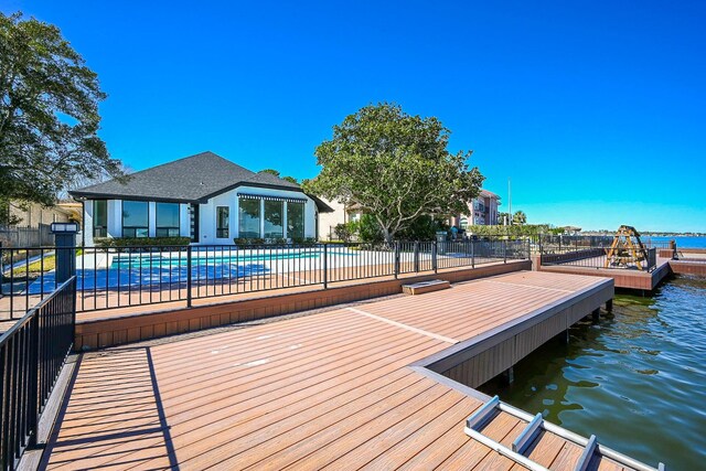 dock area featuring a water view, fence, and a fenced in pool