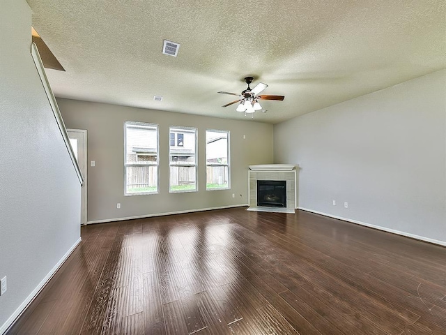 unfurnished living room with a ceiling fan, dark wood finished floors, visible vents, and a fireplace