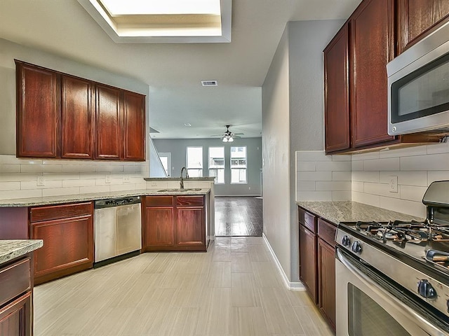 kitchen featuring stainless steel appliances, visible vents, decorative backsplash, a sink, and dark brown cabinets