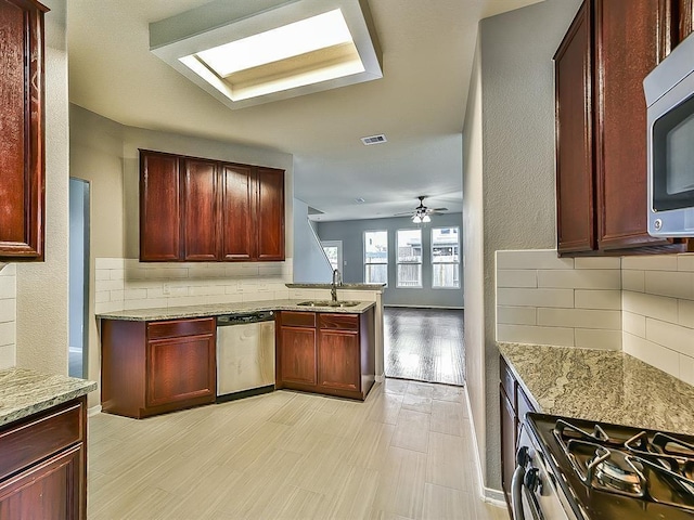 kitchen featuring reddish brown cabinets, visible vents, light stone countertops, stainless steel appliances, and a sink