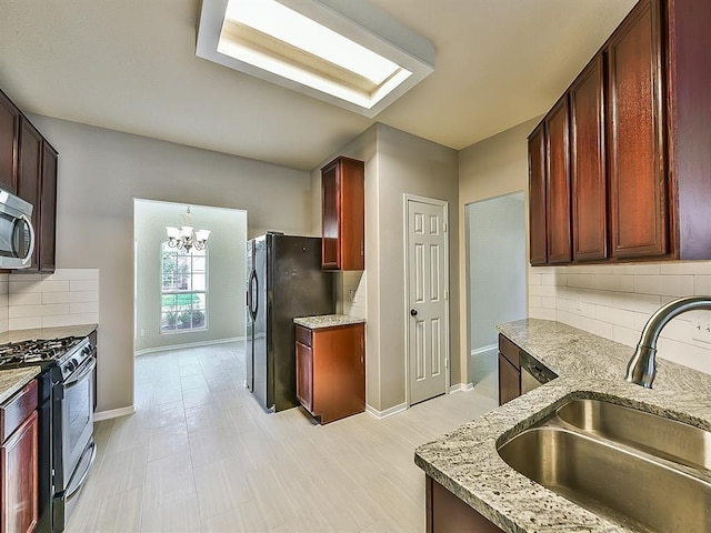 kitchen with tasteful backsplash, baseboards, light stone countertops, stainless steel appliances, and a sink