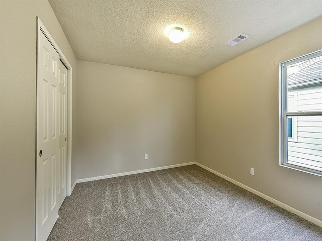 empty room featuring carpet flooring, visible vents, and baseboards