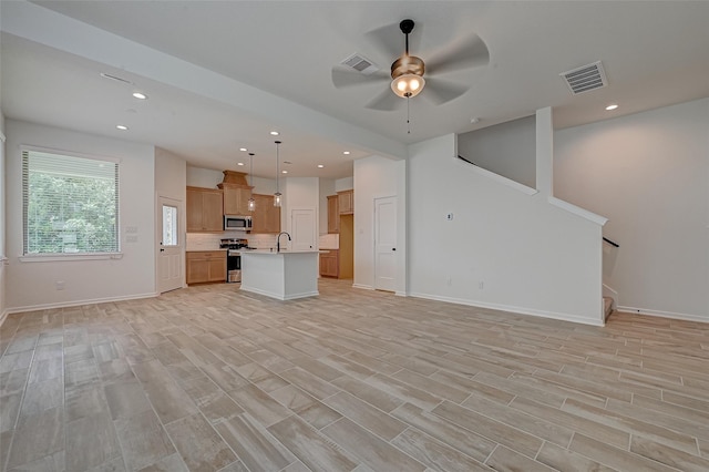 unfurnished living room with a sink, baseboards, visible vents, and a ceiling fan