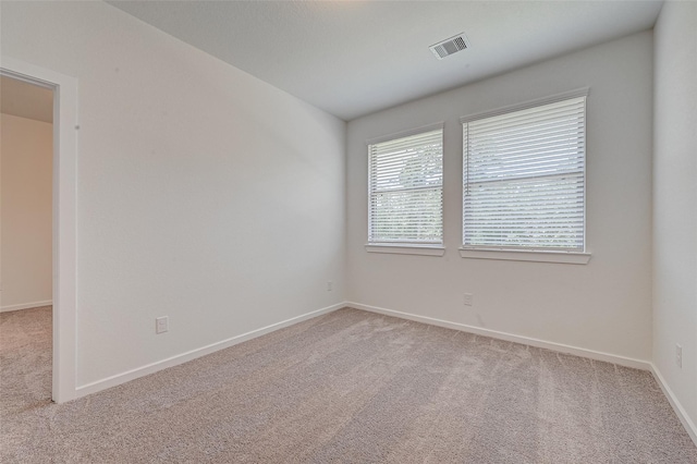 unfurnished room with visible vents, light carpet, and baseboards