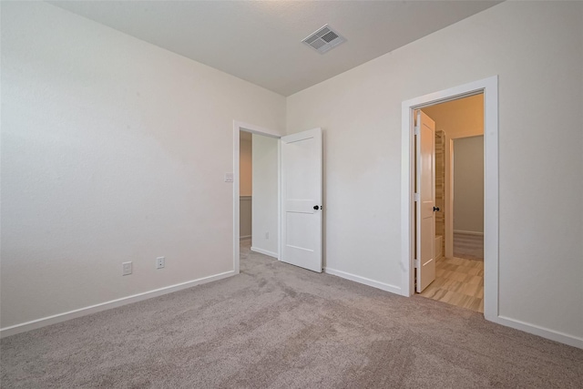 unfurnished bedroom with baseboards, connected bathroom, visible vents, and carpet flooring