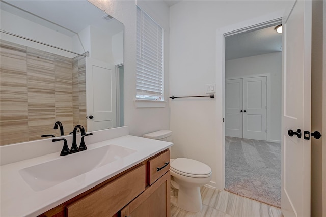 bathroom featuring walk in shower, vanity, and toilet