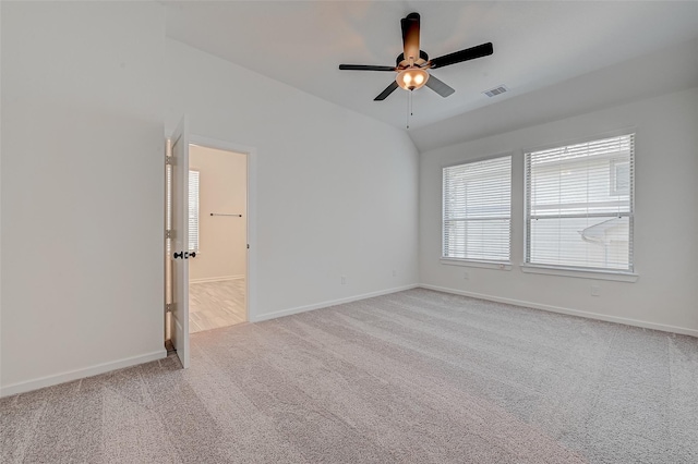 carpeted empty room featuring a ceiling fan, visible vents, vaulted ceiling, and baseboards