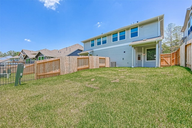 back of property with a fenced backyard, central AC, and a yard