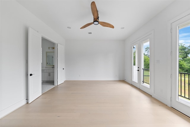 empty room with ceiling fan, light wood-style flooring, and baseboards