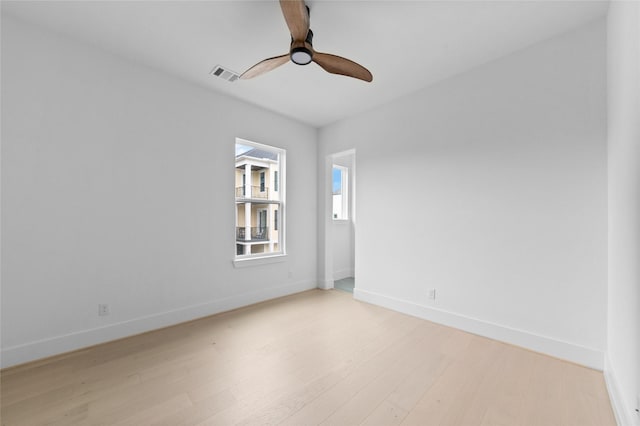 spare room with baseboards, visible vents, ceiling fan, and light wood finished floors