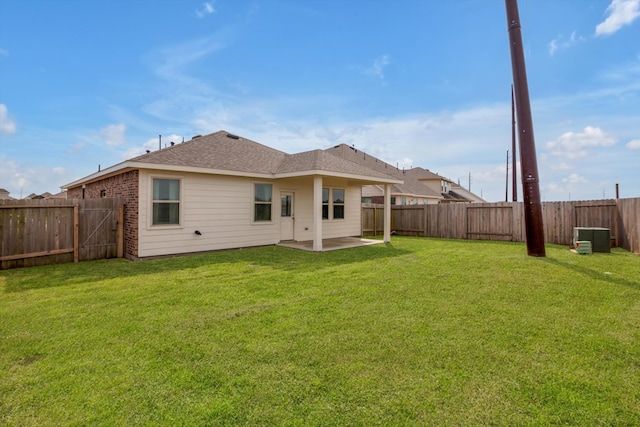 back of house with a fenced backyard, a lawn, and brick siding