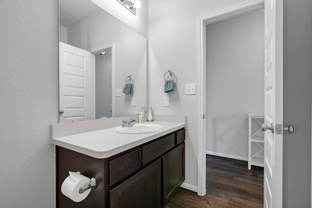 bathroom with wood finished floors, vanity, and baseboards