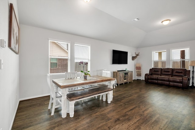 dining space with visible vents, vaulted ceiling, baseboards, and wood finished floors