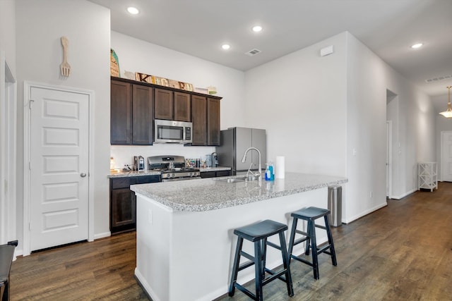 kitchen with visible vents, dark wood finished floors, stainless steel appliances, dark brown cabinets, and a sink