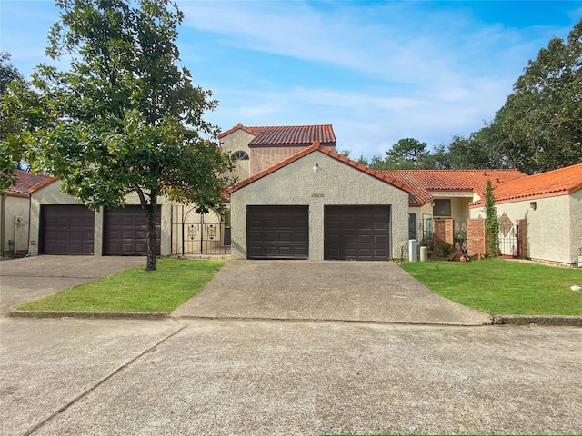 mediterranean / spanish-style home with stucco siding, a tile roof, an attached garage, fence, and a front yard