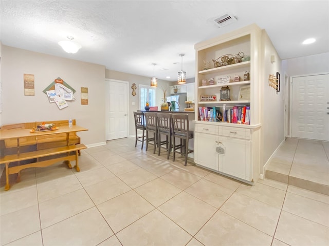 kitchen featuring light tile patterned floors, visible vents, white cabinetry, and baseboards