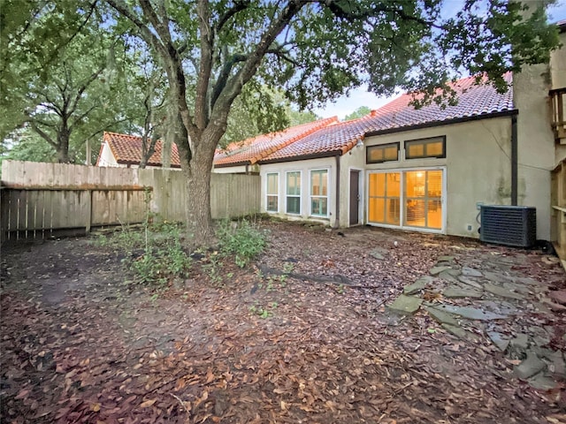 rear view of house with fence, a tiled roof, and stucco siding