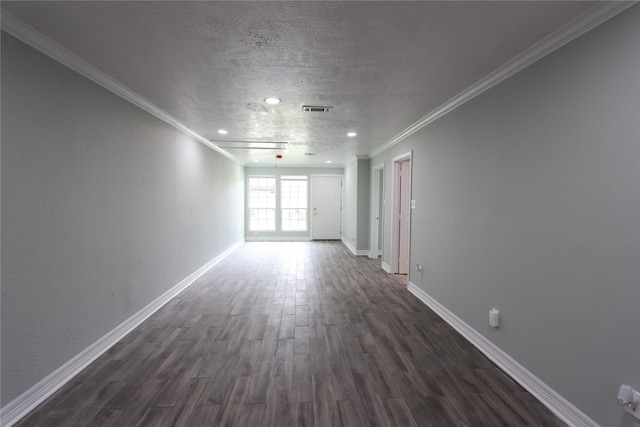 empty room with a textured ceiling, visible vents, baseboards, ornamental molding, and dark wood finished floors