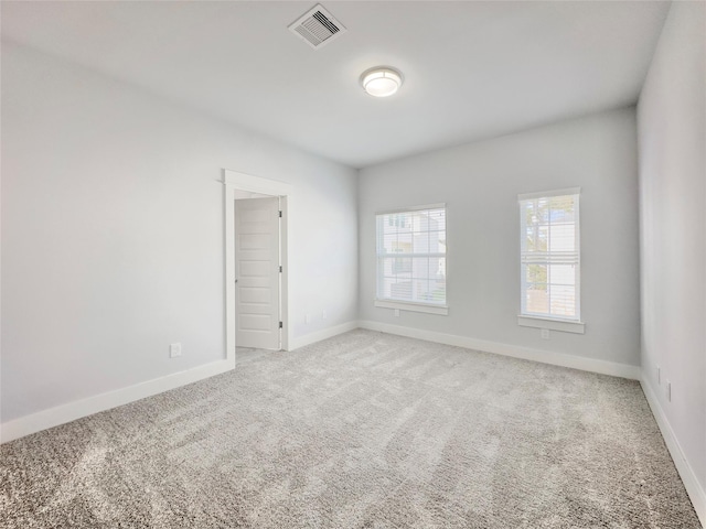 spare room featuring baseboards, visible vents, and light colored carpet