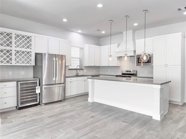 kitchen featuring beverage cooler, stainless steel appliances, premium range hood, a sink, and visible vents