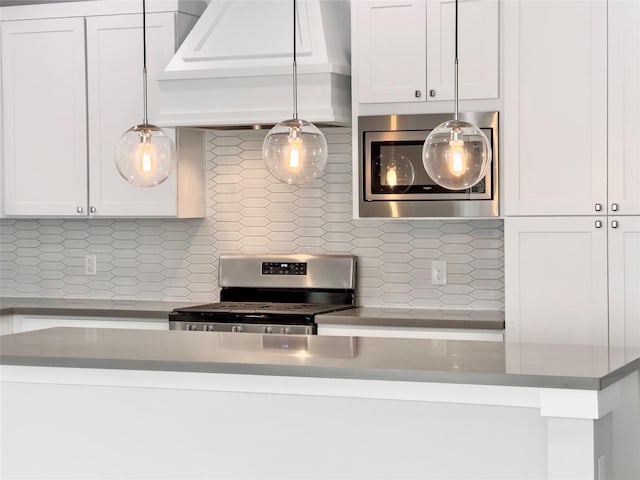 kitchen featuring stainless steel appliances, tasteful backsplash, custom range hood, hanging light fixtures, and white cabinetry